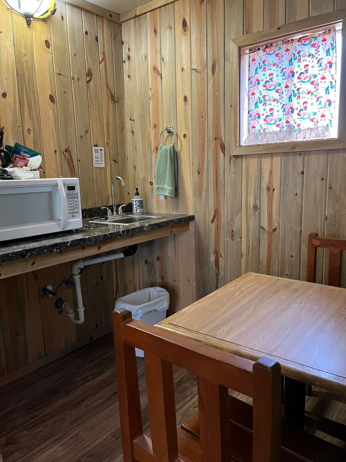 A kitchen with a microwave , sink , table and chairs.