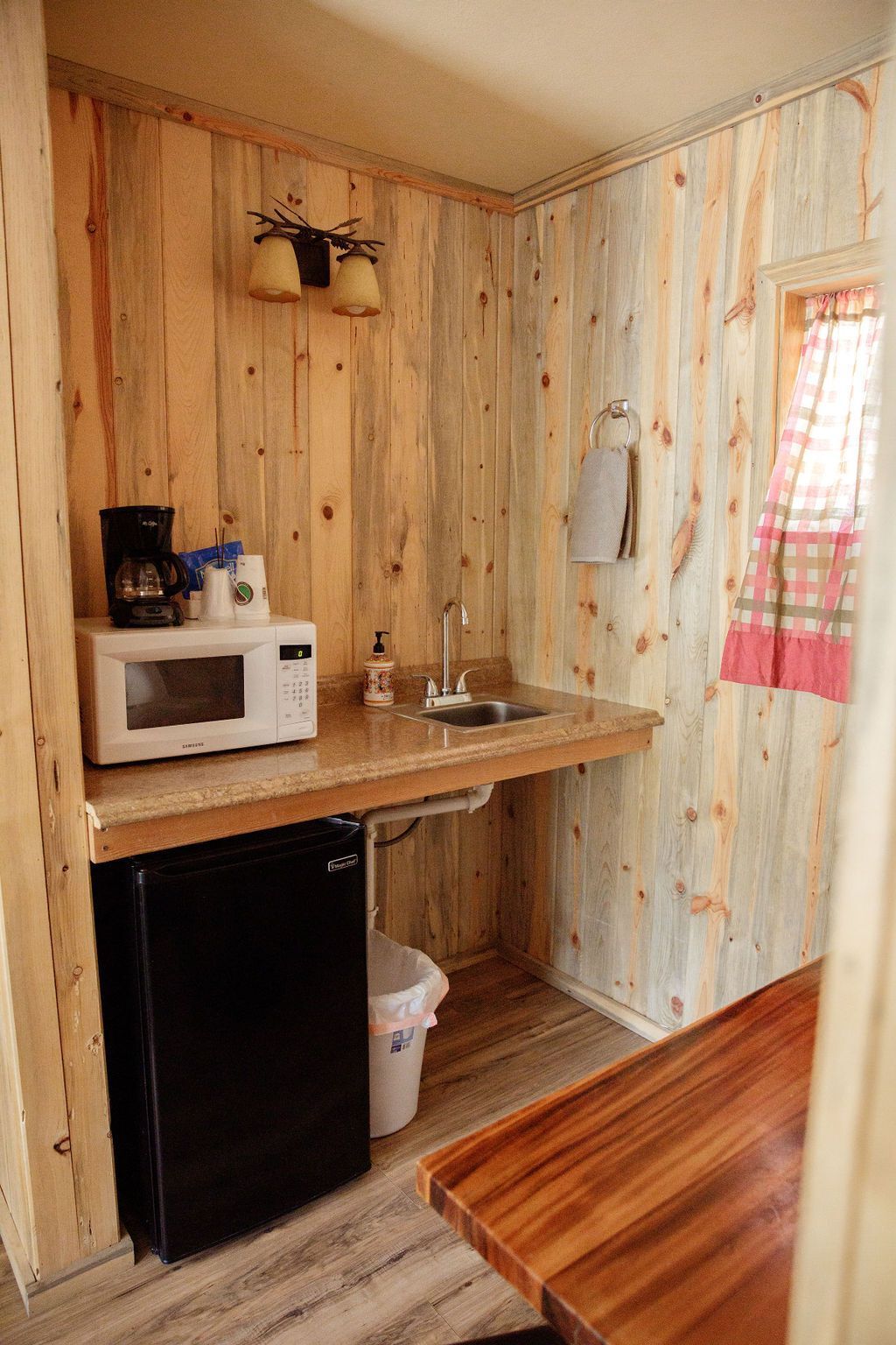 A kitchen with a microwave , refrigerator , sink and table.