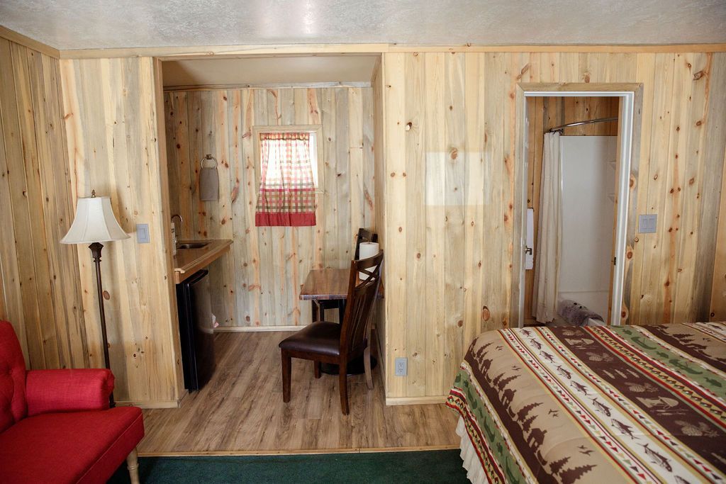 A hotel room with a bed , chair , table and lamp.