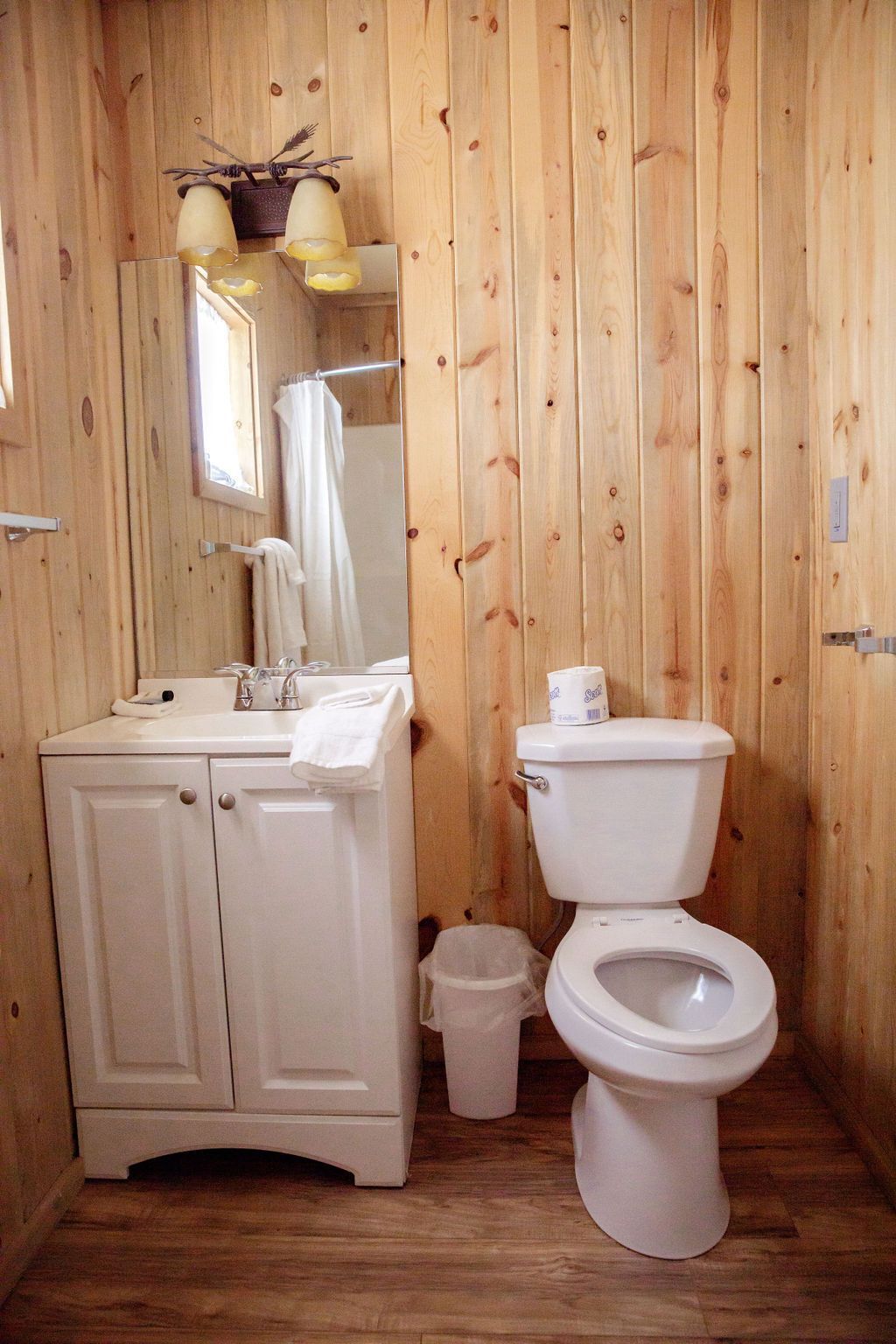 A bathroom with a toilet , sink and mirror.