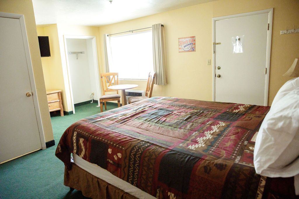 A hotel room with a king size bed and a table and chairs.