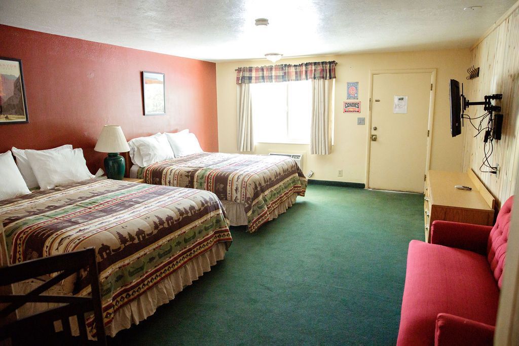 A hotel room with two beds and a red couch