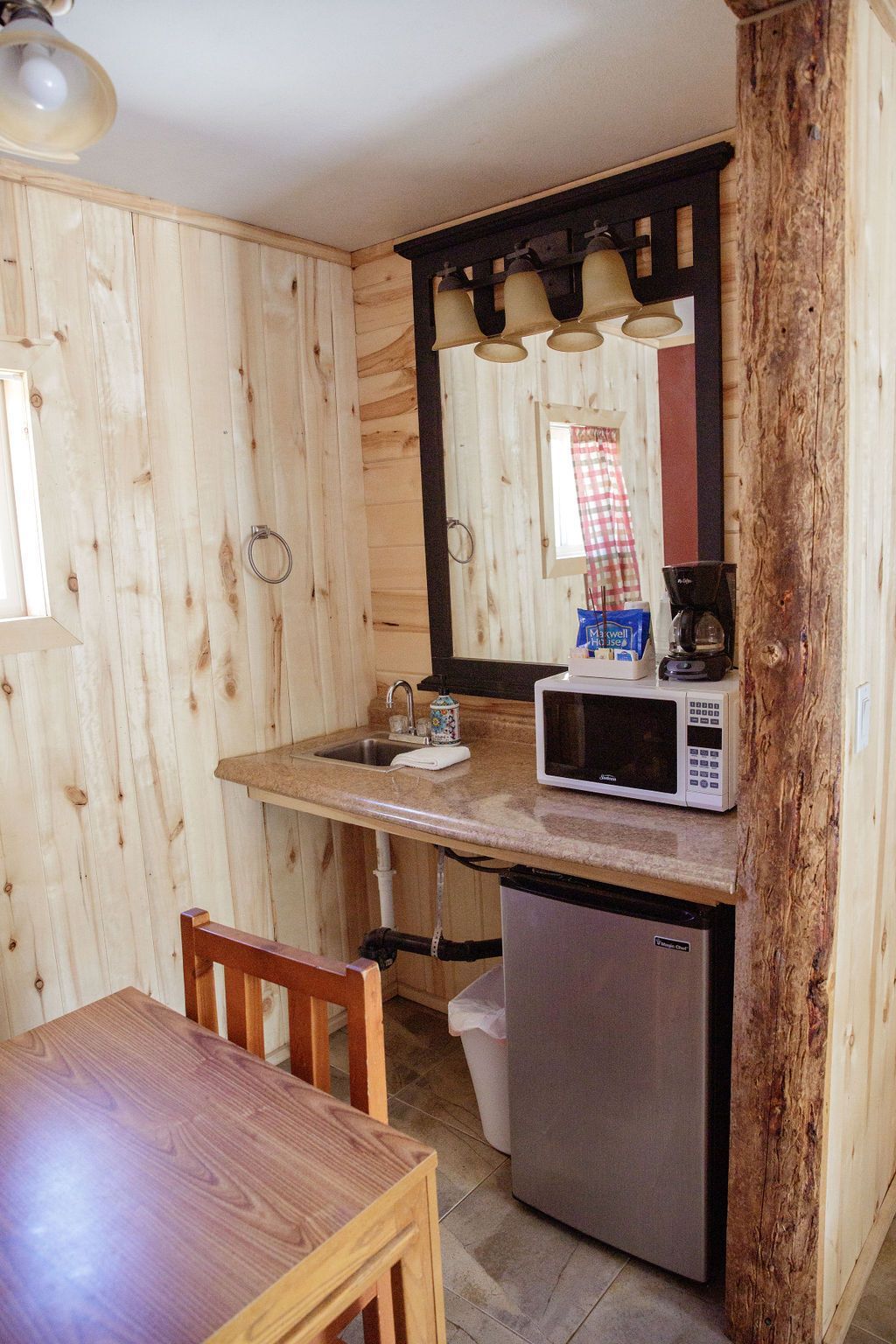 A kitchen with a microwave , refrigerator , sink and mirror.