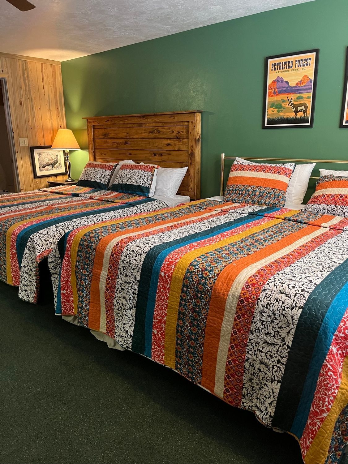 A hotel room with three beds and a ceiling fan.