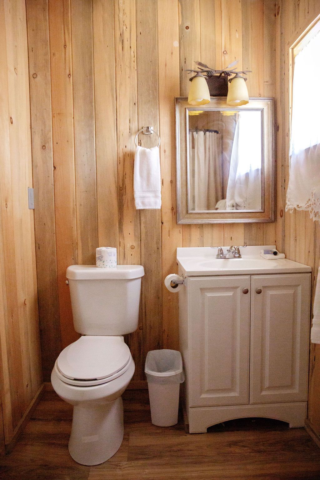 A bathroom with a toilet , sink and mirror.