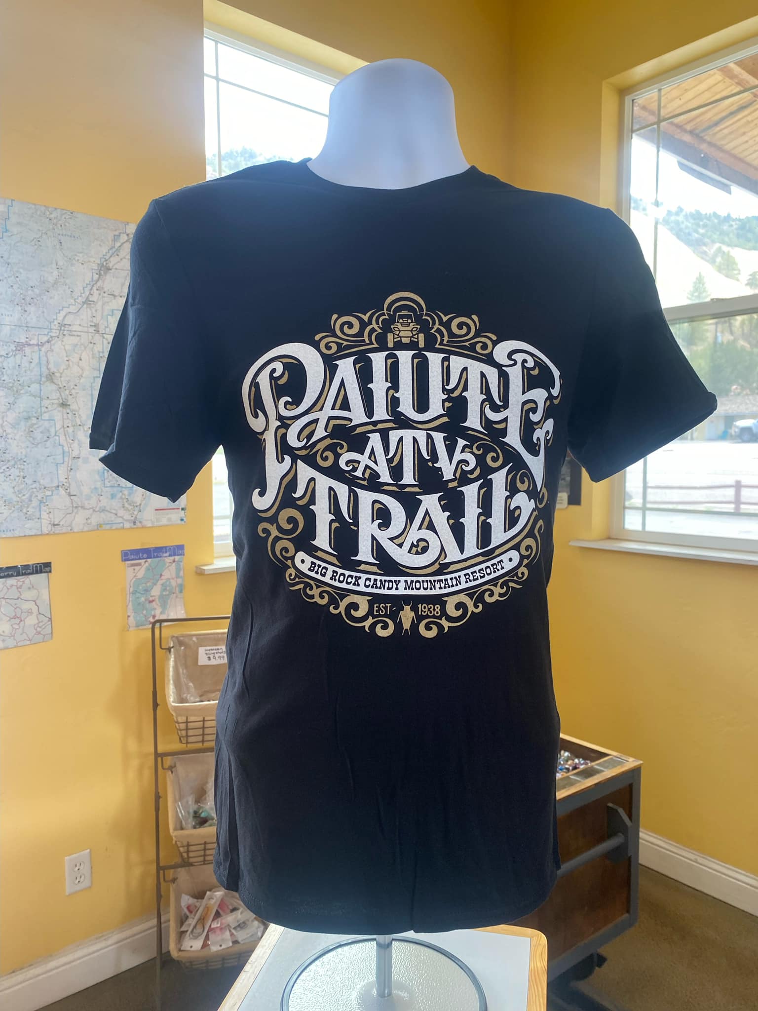 A black t-shirt is on a mannequin in a room.