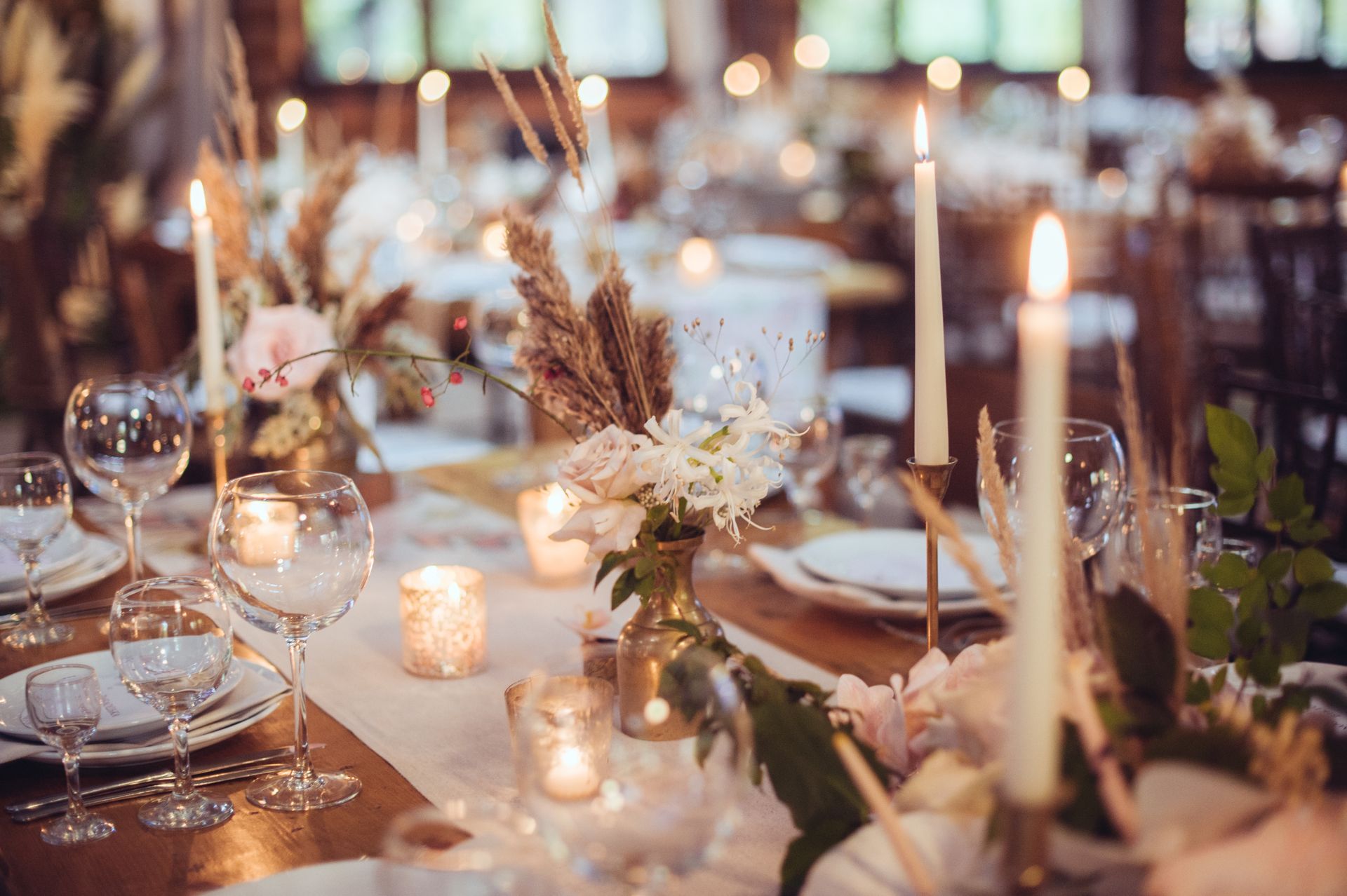 A table set for a wedding reception with candles and flowers on it.