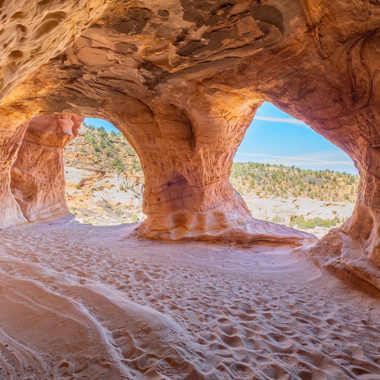 a cave in the desert with a view of the sky through a window .