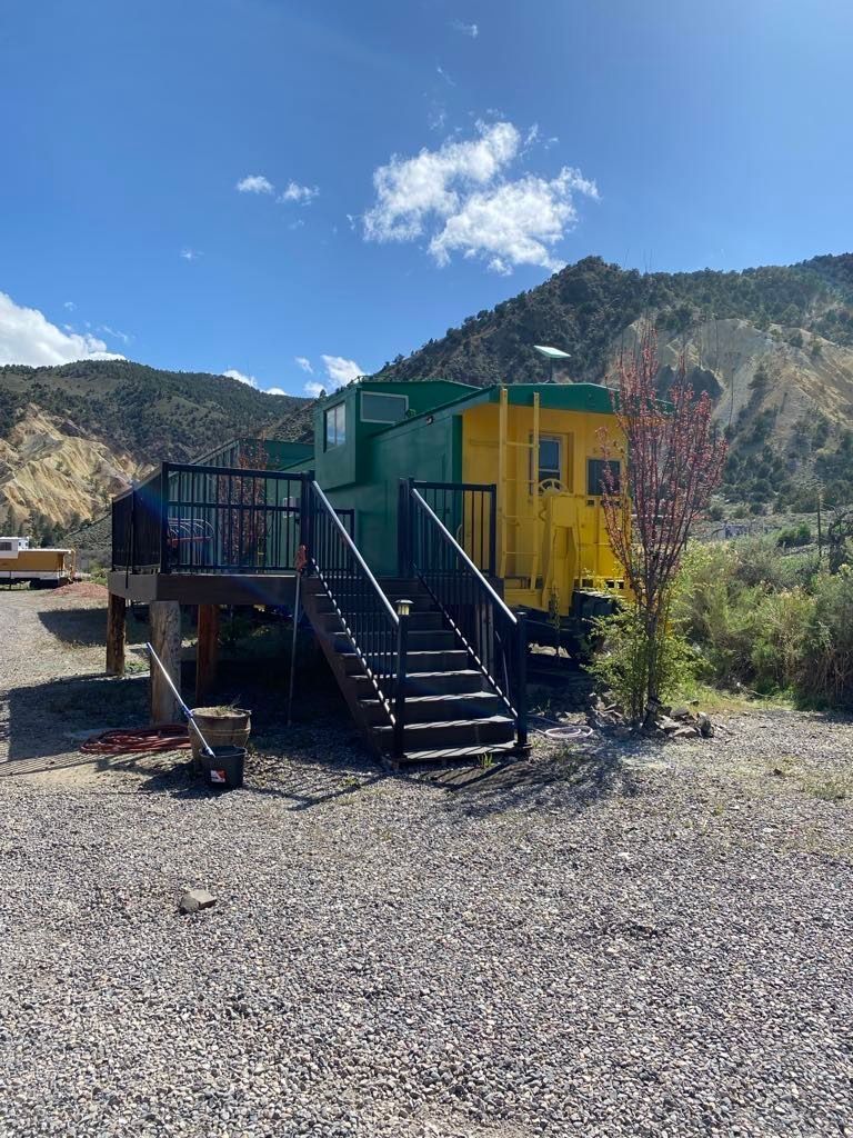 A green and yellow train car with stairs leading up to it.