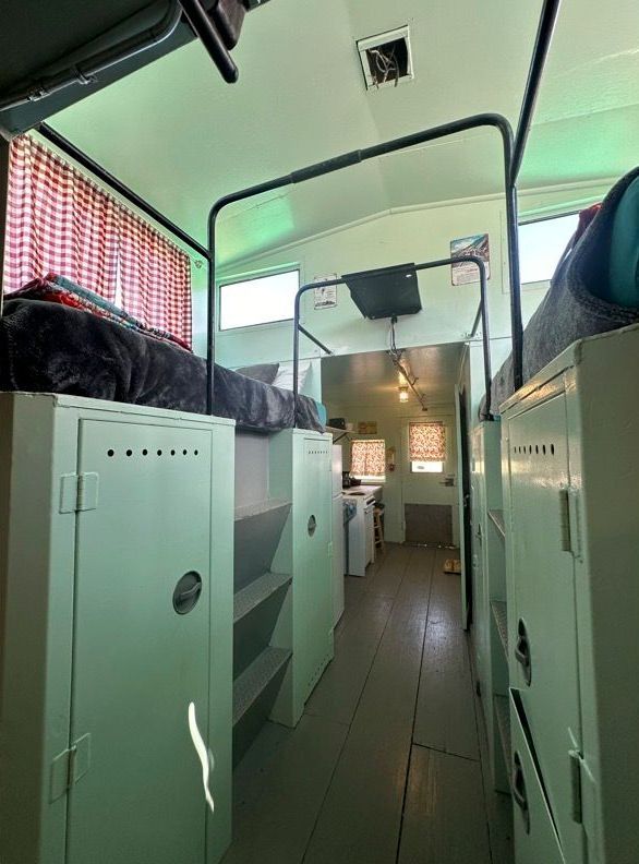 The inside of a school bus with bunk beds and lockers.