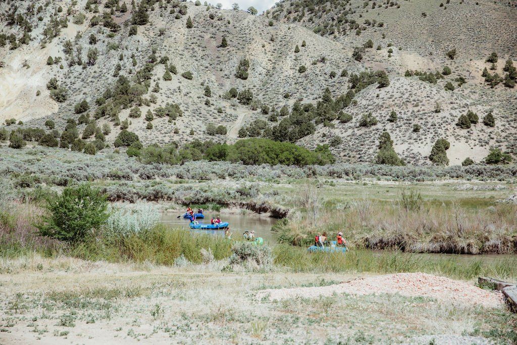 A group of people are rafting down a river in the desert.