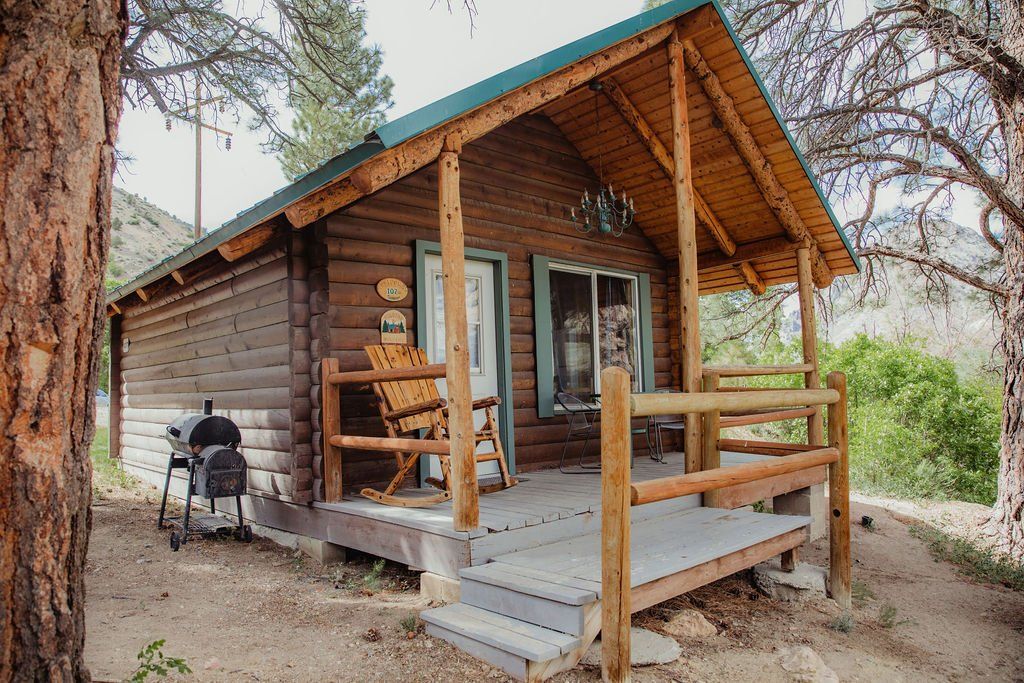 a small log cabin with a porch and rocking chairs .