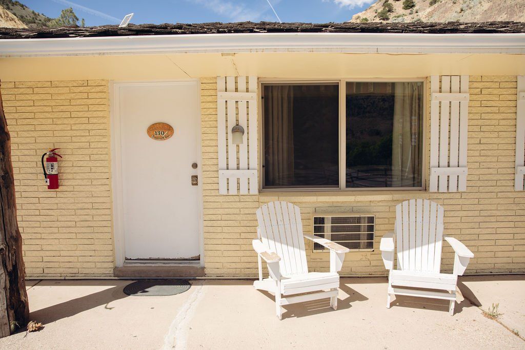 A yellow motel with two white chairs in front of it
