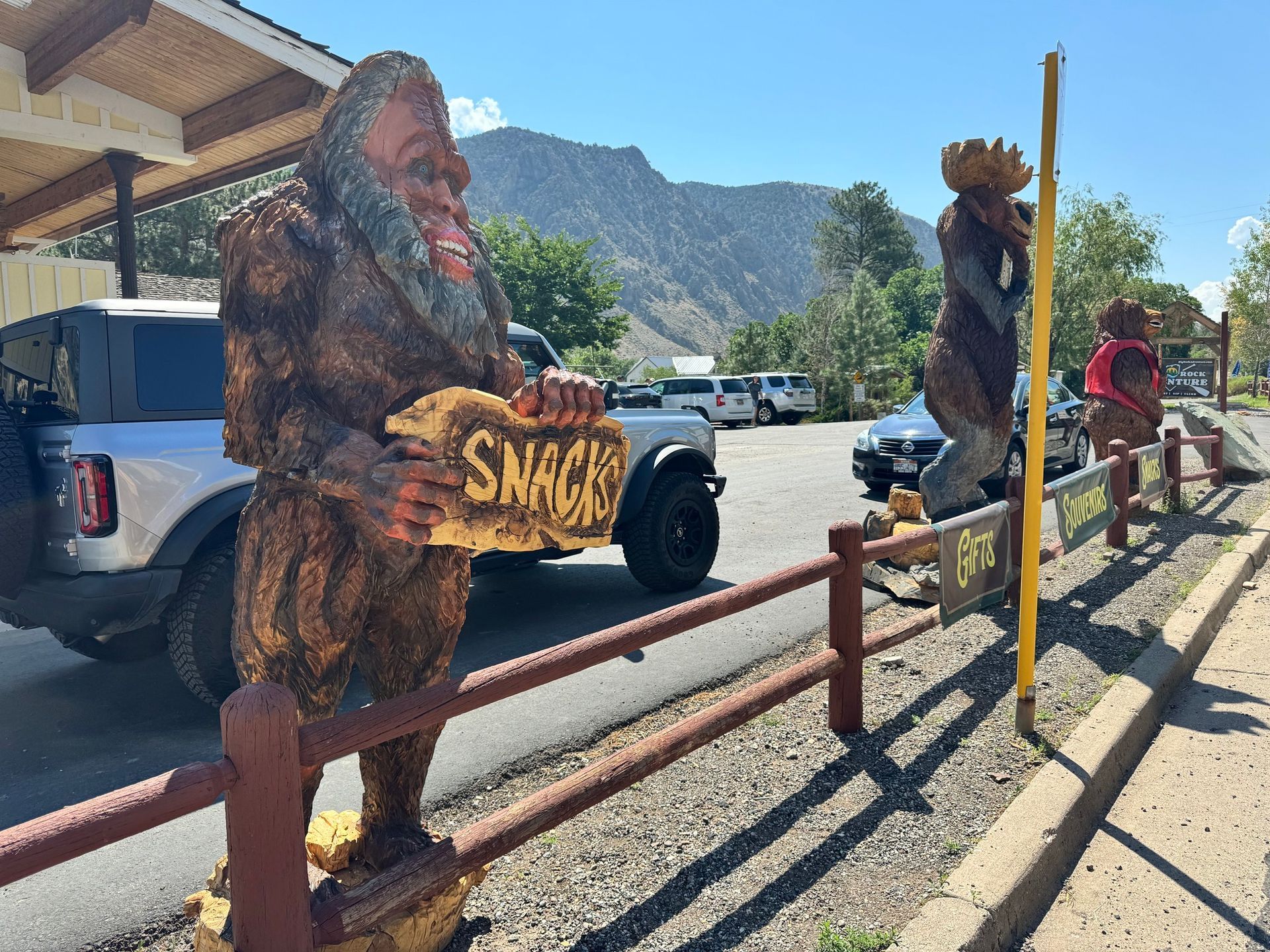 A statue of a bigfoot holding a sign that says snacks.