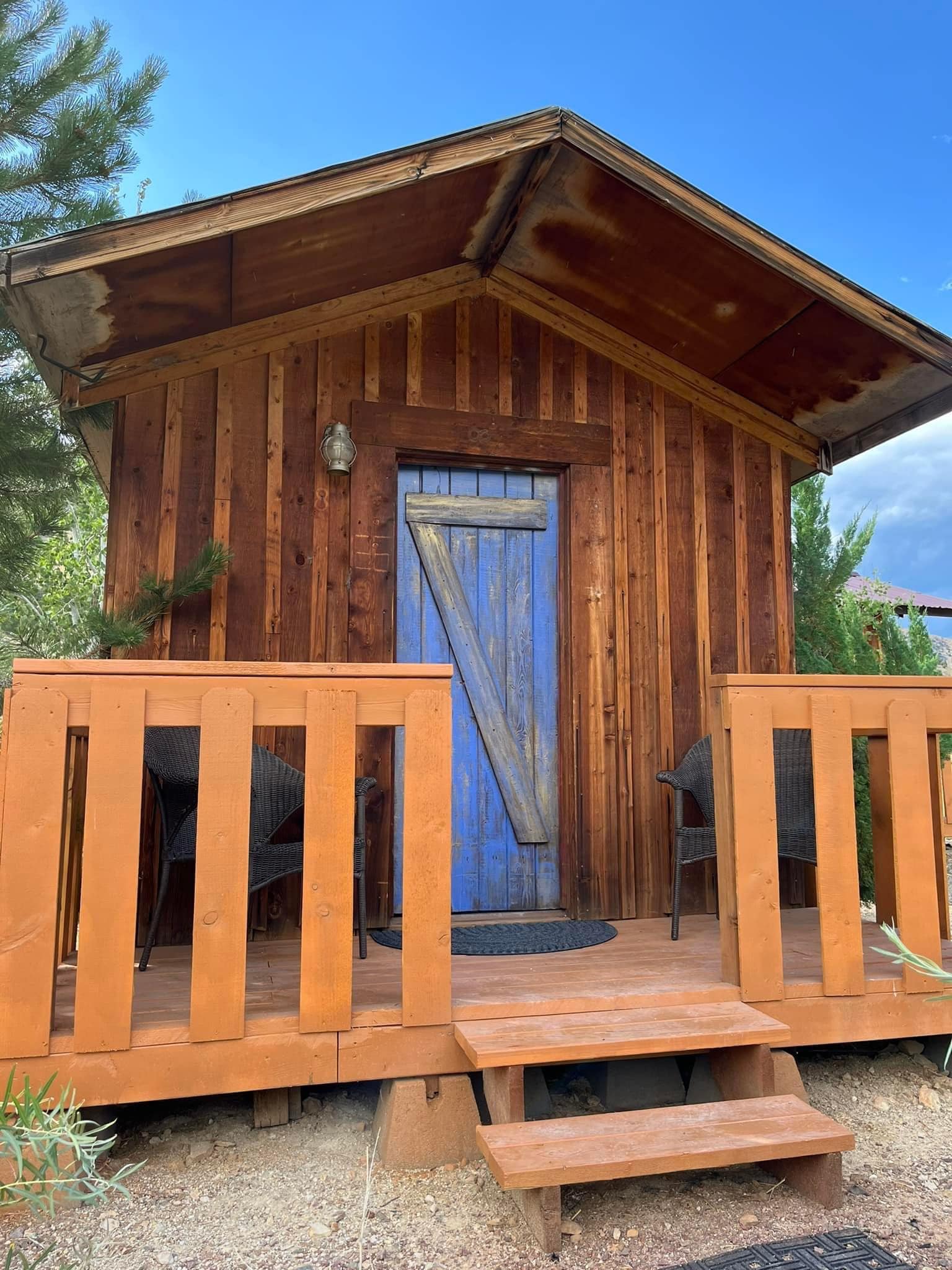 A small wooden cabin with a blue door and stairs.