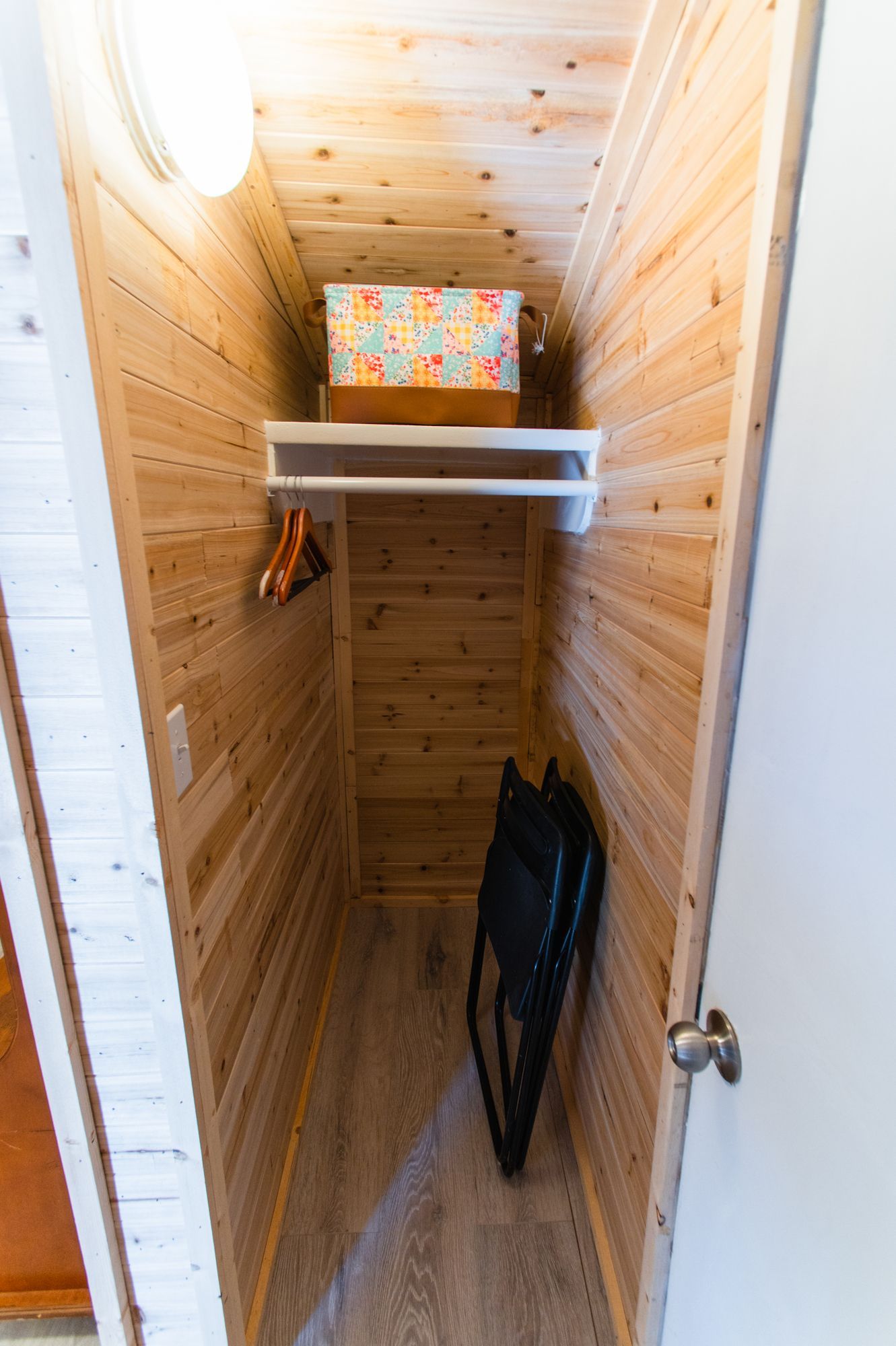 A small closet with a chair and a box on the shelf.