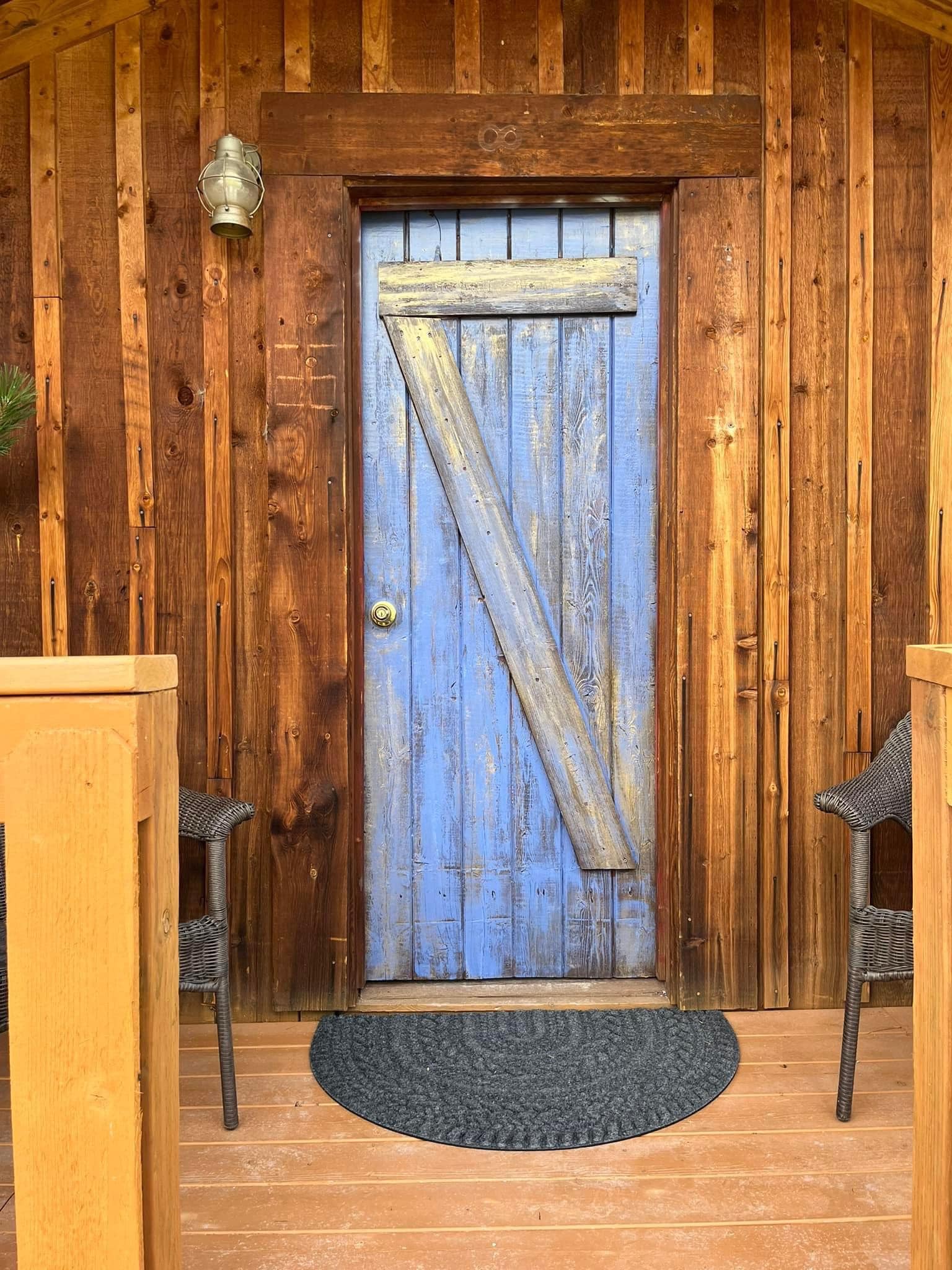 A blue door with a v on it is on a wooden house