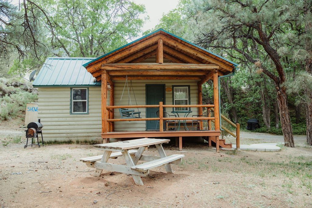 A small cabin with a picnic table on the porch.