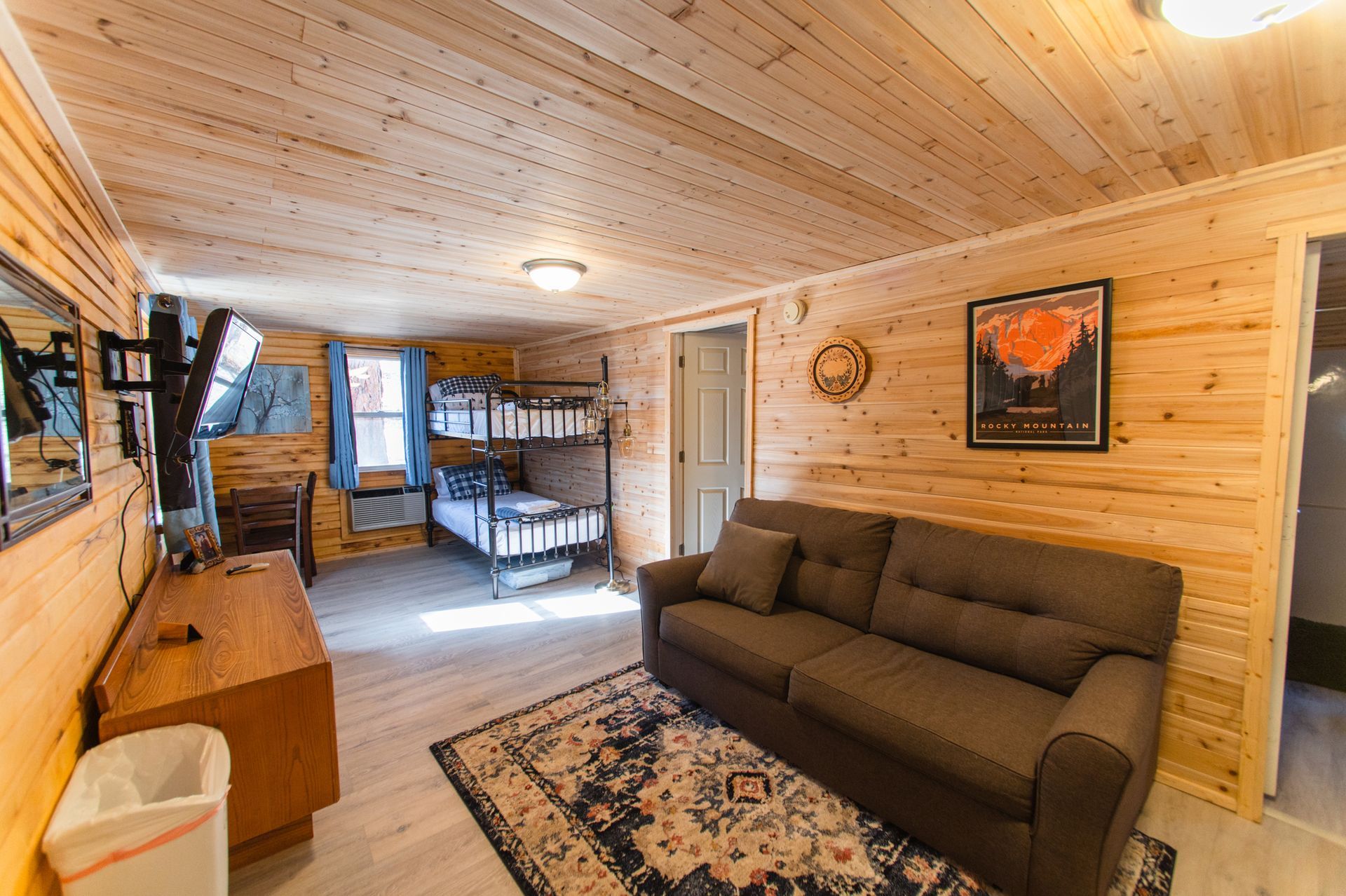 A living room with a couch and bunk beds in a cabin.