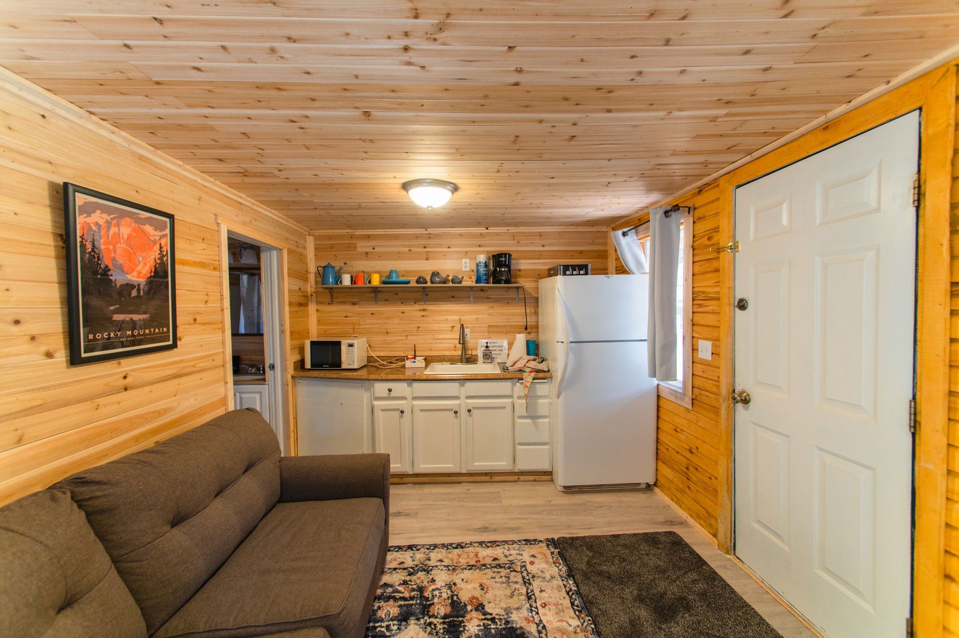 A living room with a couch , refrigerator , and kitchen.