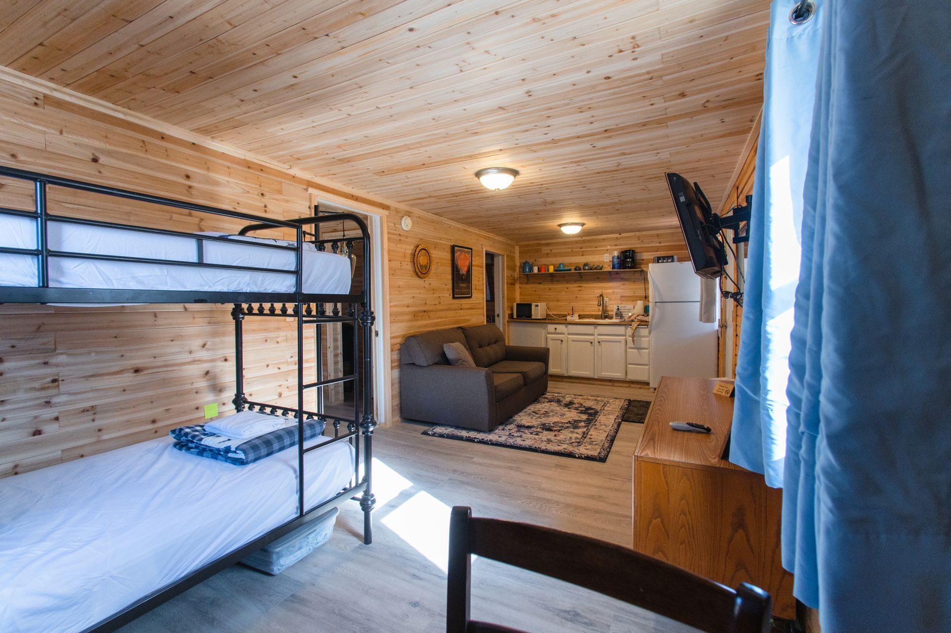 A room with bunk beds , a couch , a desk and a television.