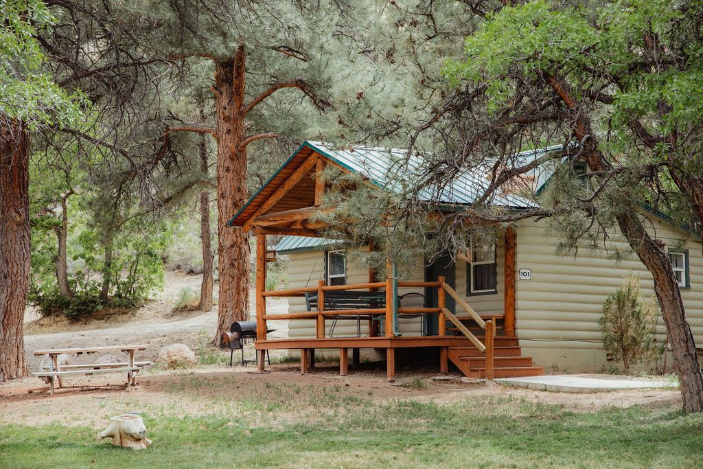 A small cabin with a porch in the middle of a forest.