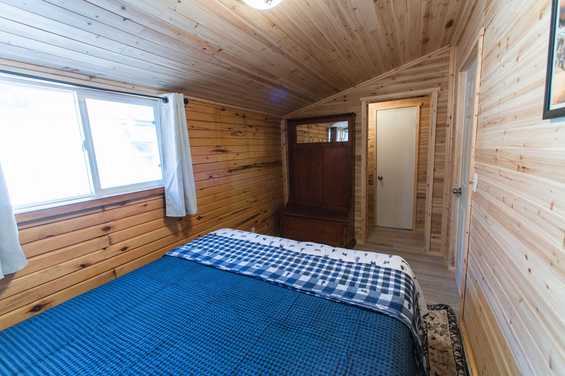 A bedroom in a cabin with a bed and a window.