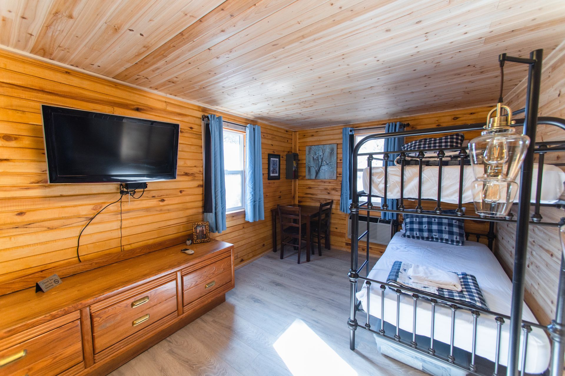 A bedroom in a log cabin with a bed , television and dresser.