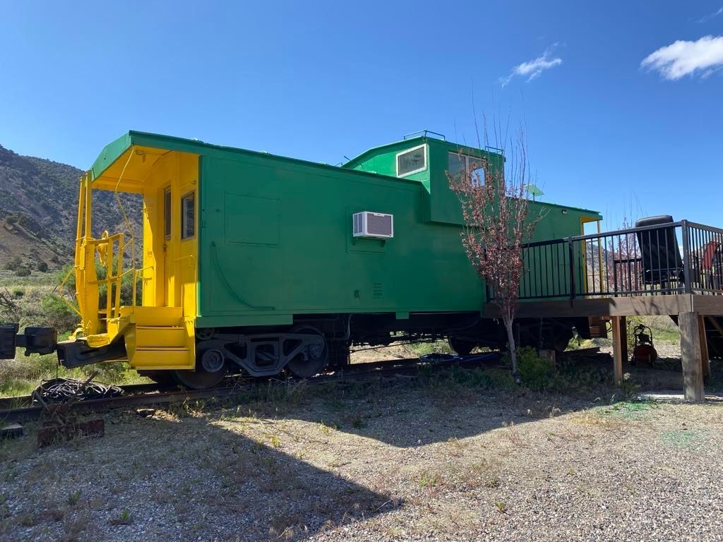 A green and yellow train car with a deck attached to it.