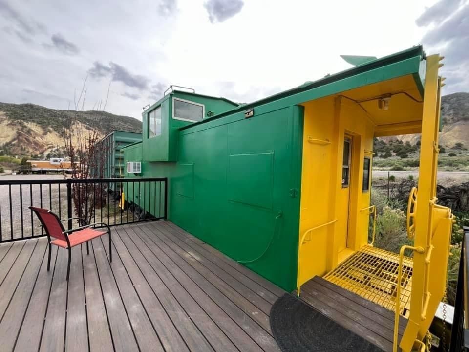 A green and yellow building with a balcony and chairs on it.