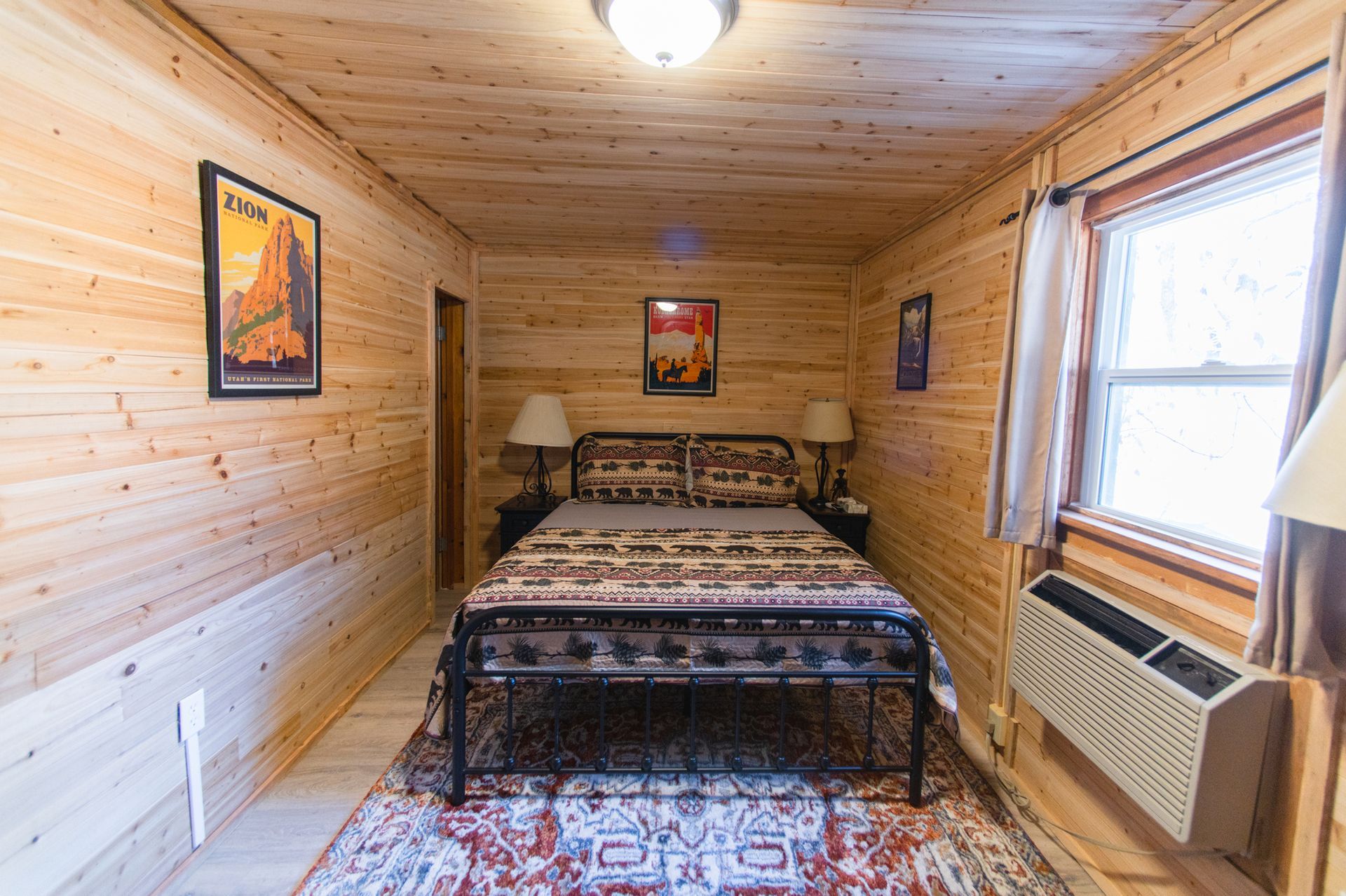 A bedroom with a bed , lamps , a rug and a window.