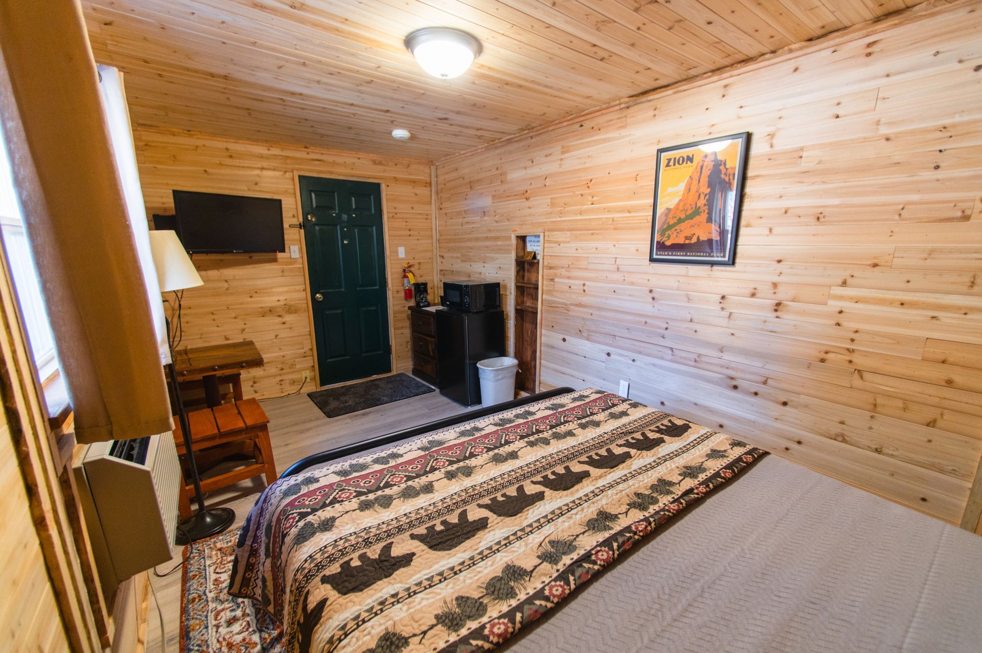 A bedroom in a log cabin with a bed and a television.