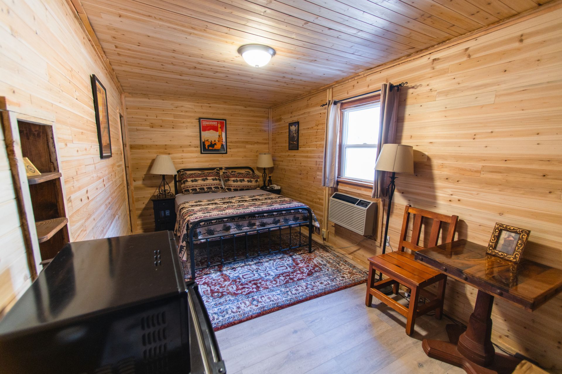 A bedroom with a bed , chair , table and microwave.