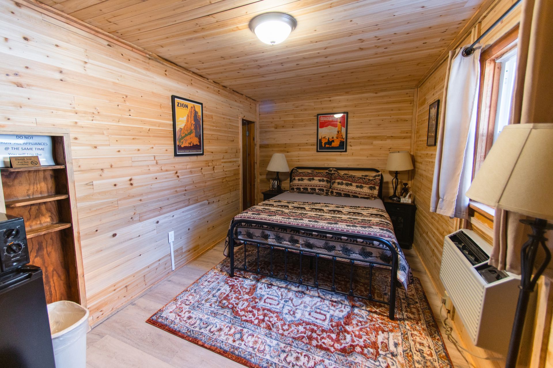 A bedroom with a bed , lamps , and a rug.