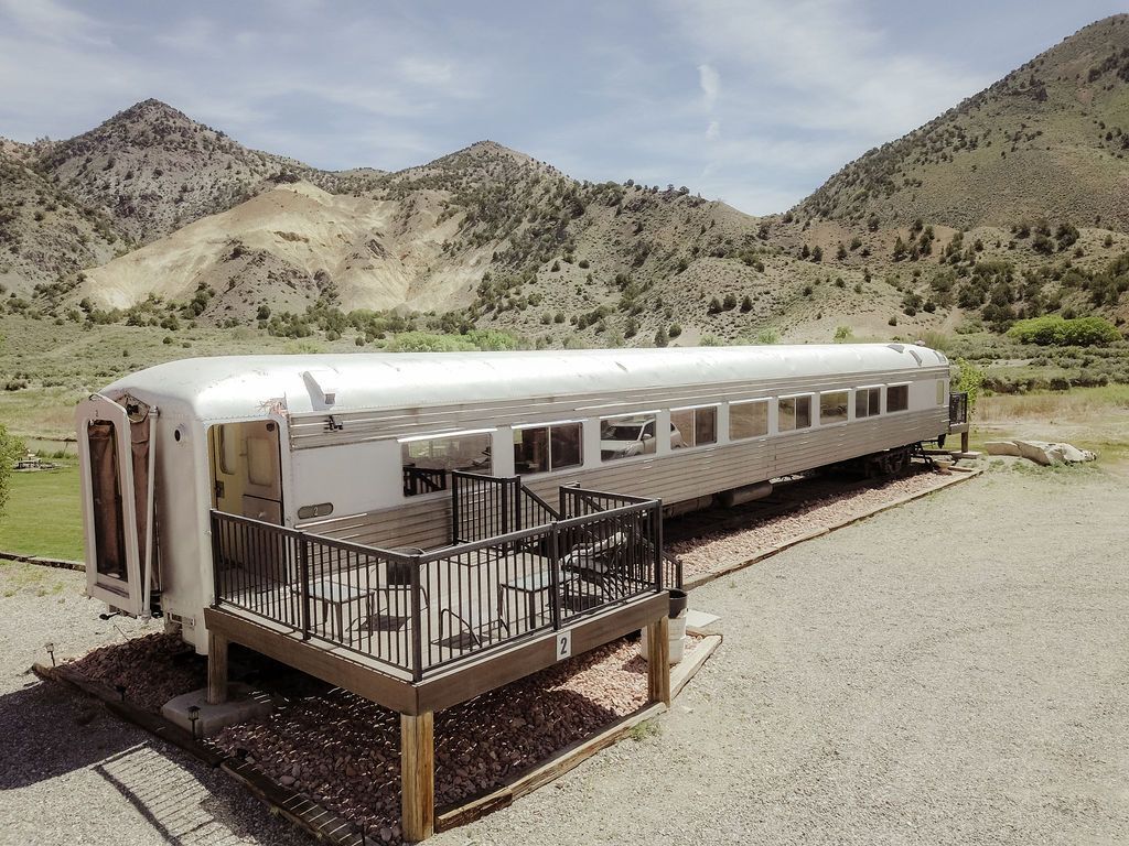 A train car with a deck and mountains in the background