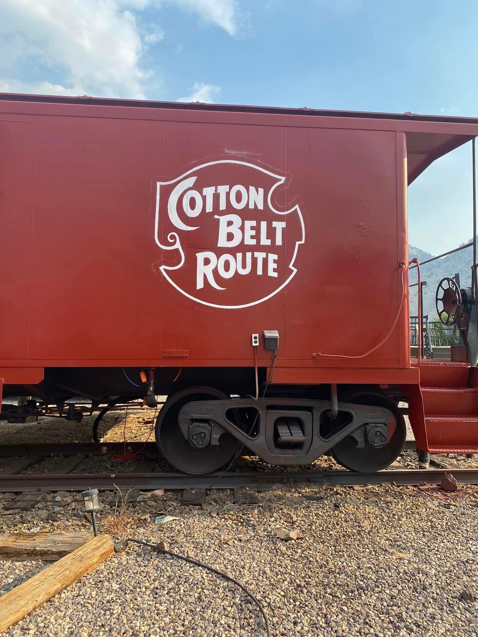 A red cotton belt route train car is parked on the tracks.