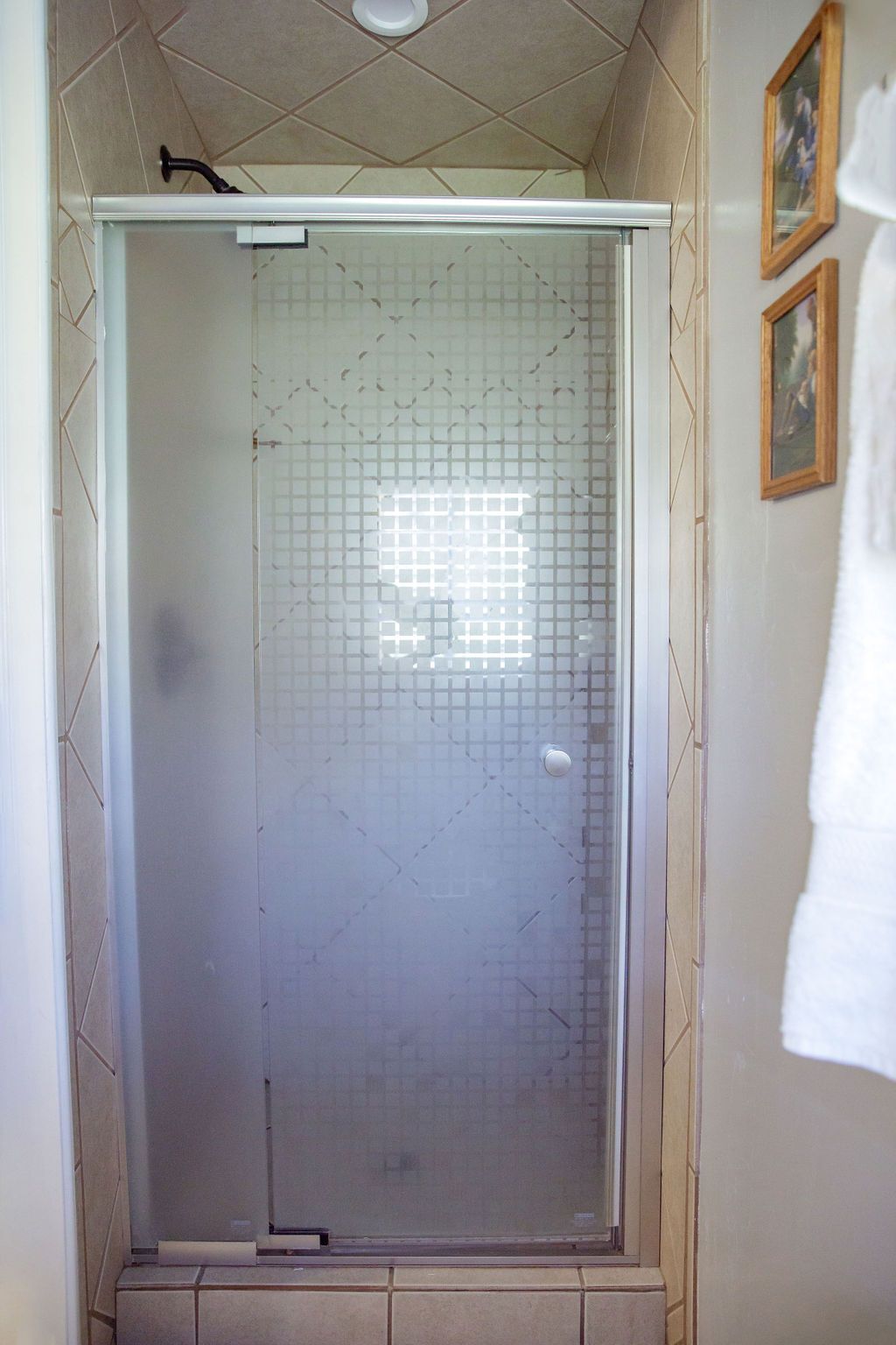 A bathroom with a sliding glass shower door and a window.