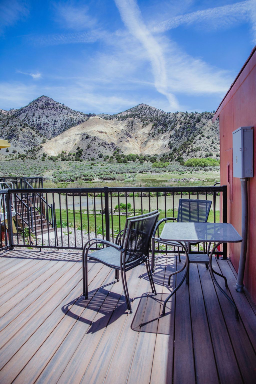 A deck with a table and chairs and mountains in the background.