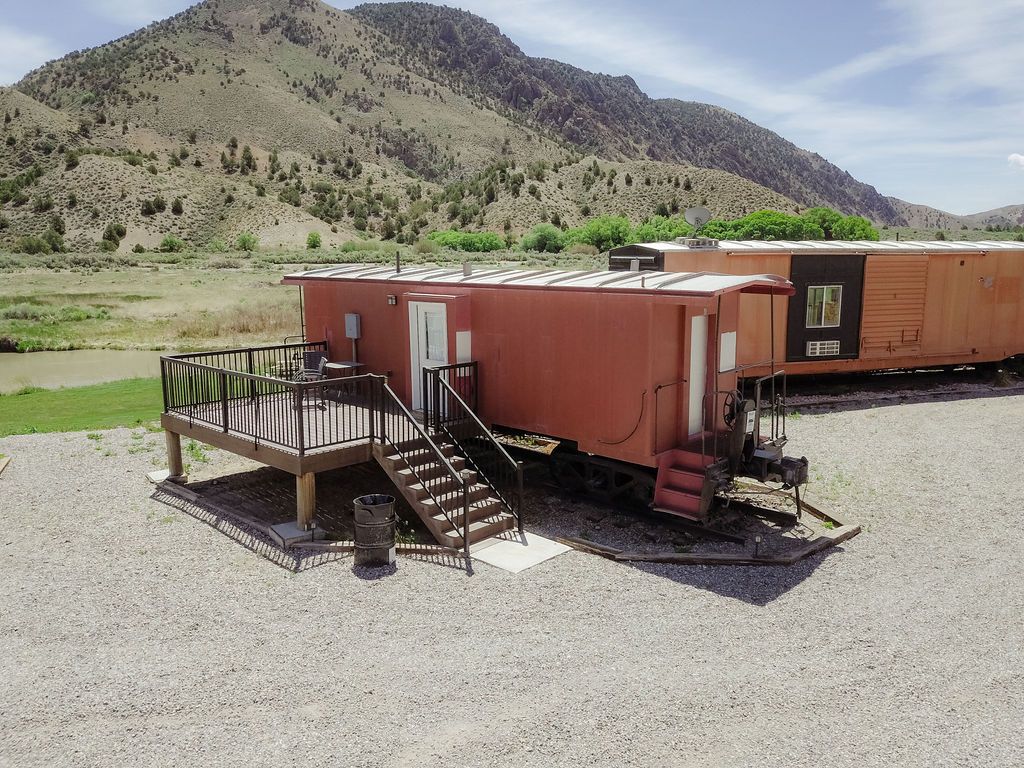 A train car has been converted into a house with a deck and stairs.