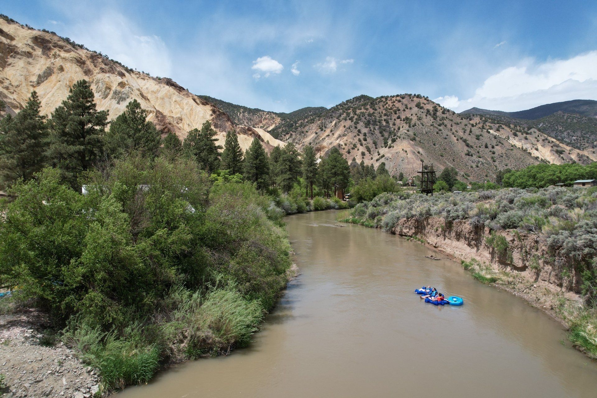 Two rafts are floating down a river surrounded by mountains.