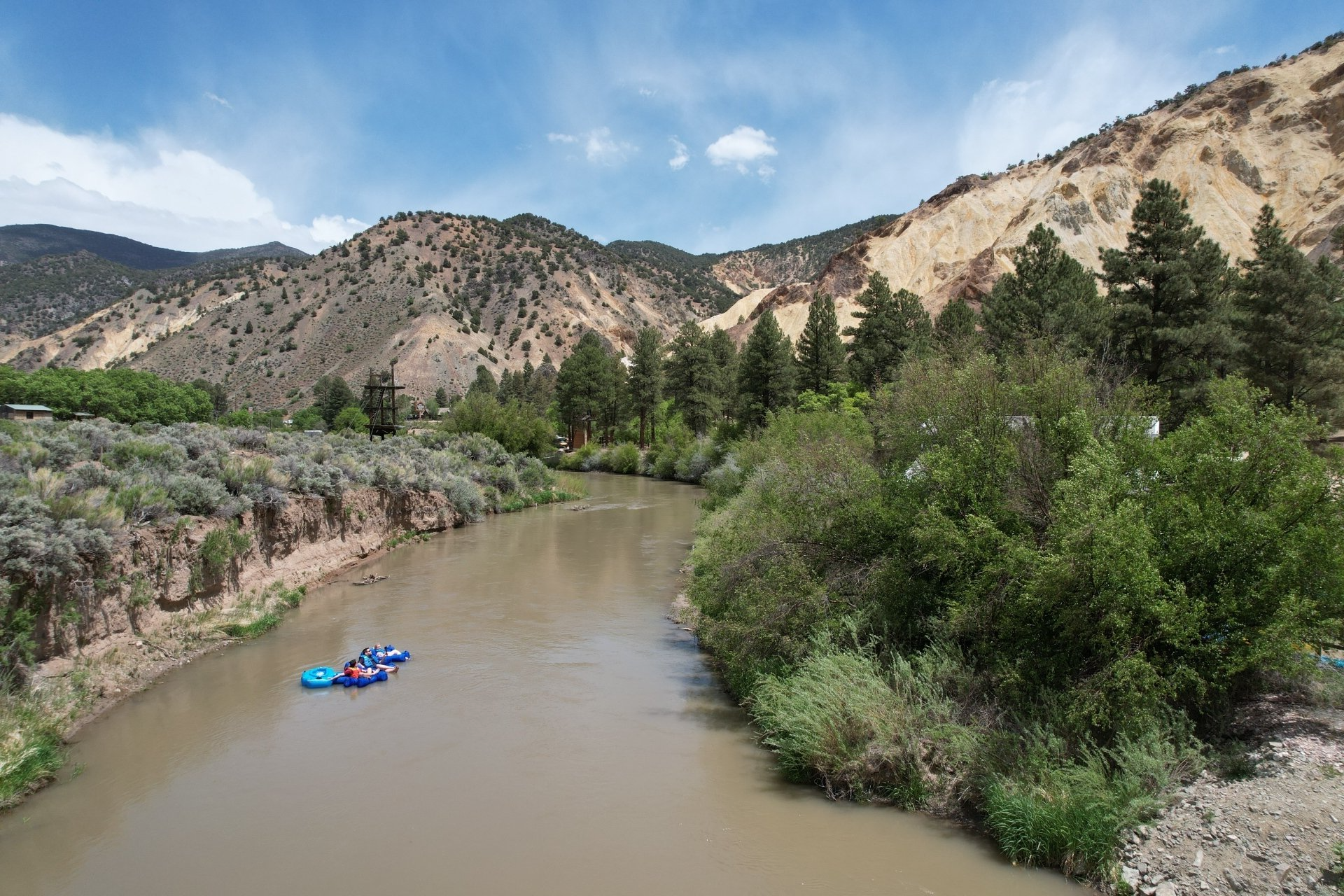 A couple of rafts are floating down a river surrounded by mountains.