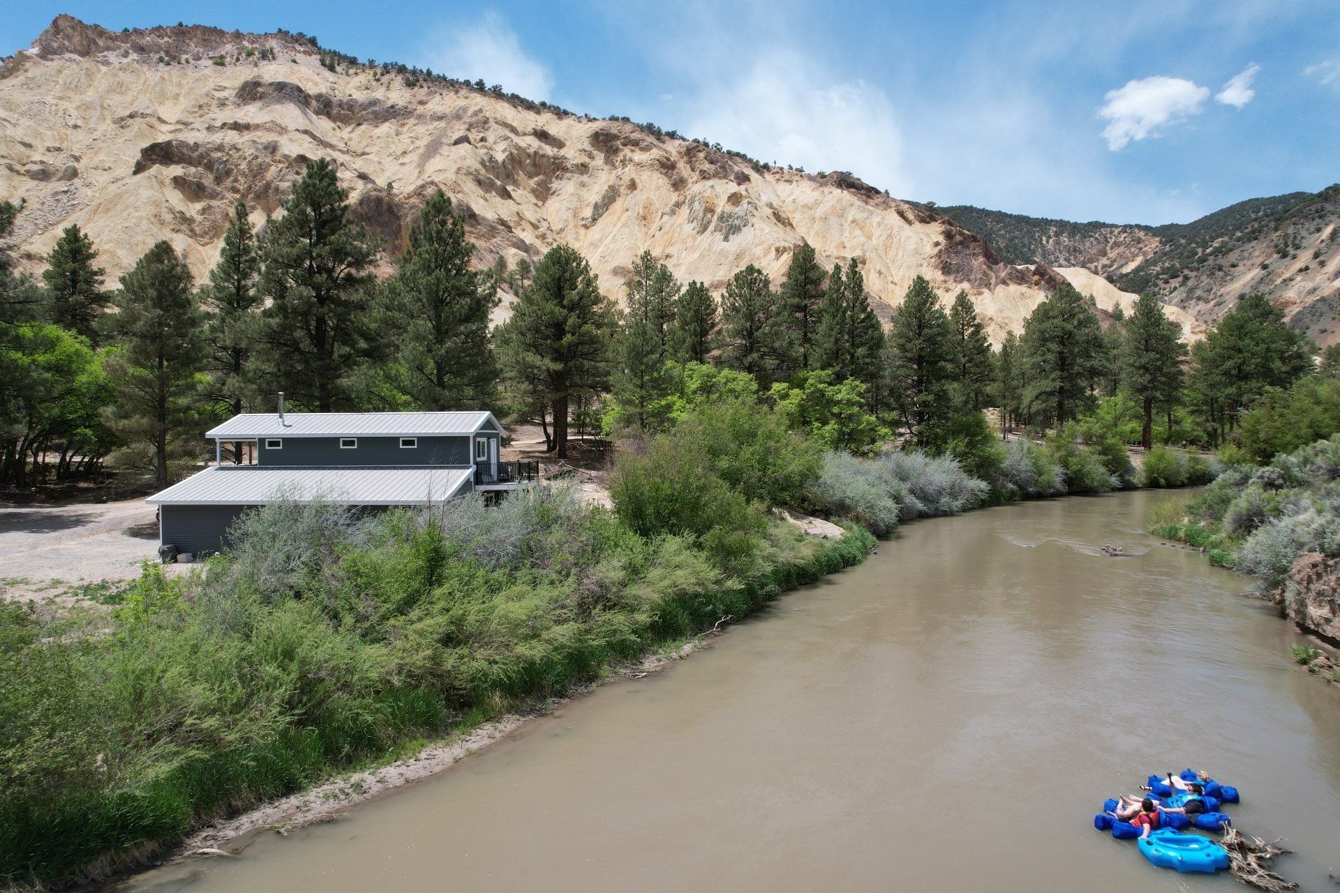 A river with a house in the background and rafts in the water.