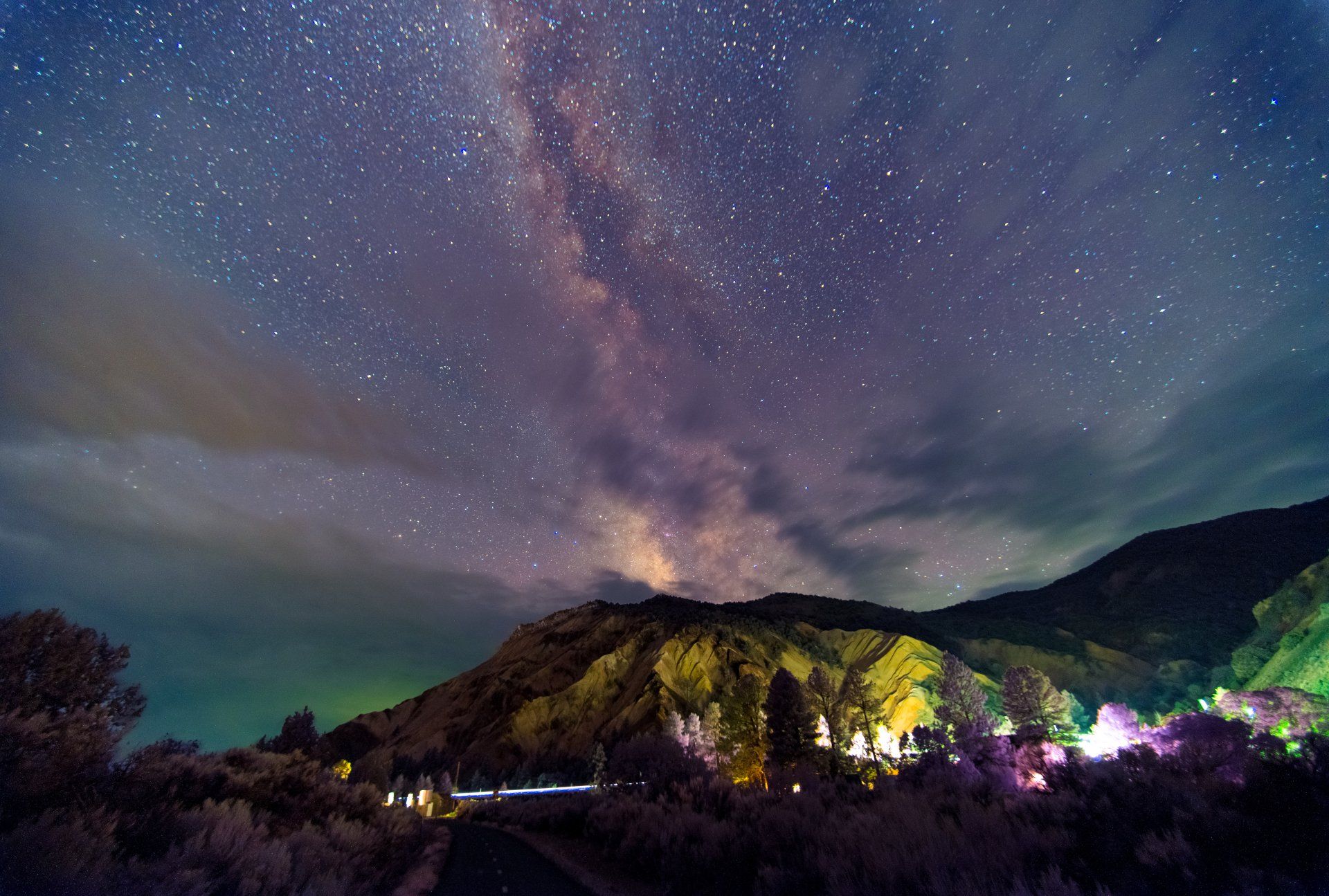 A night sky filled with lots of stars over a mountain.