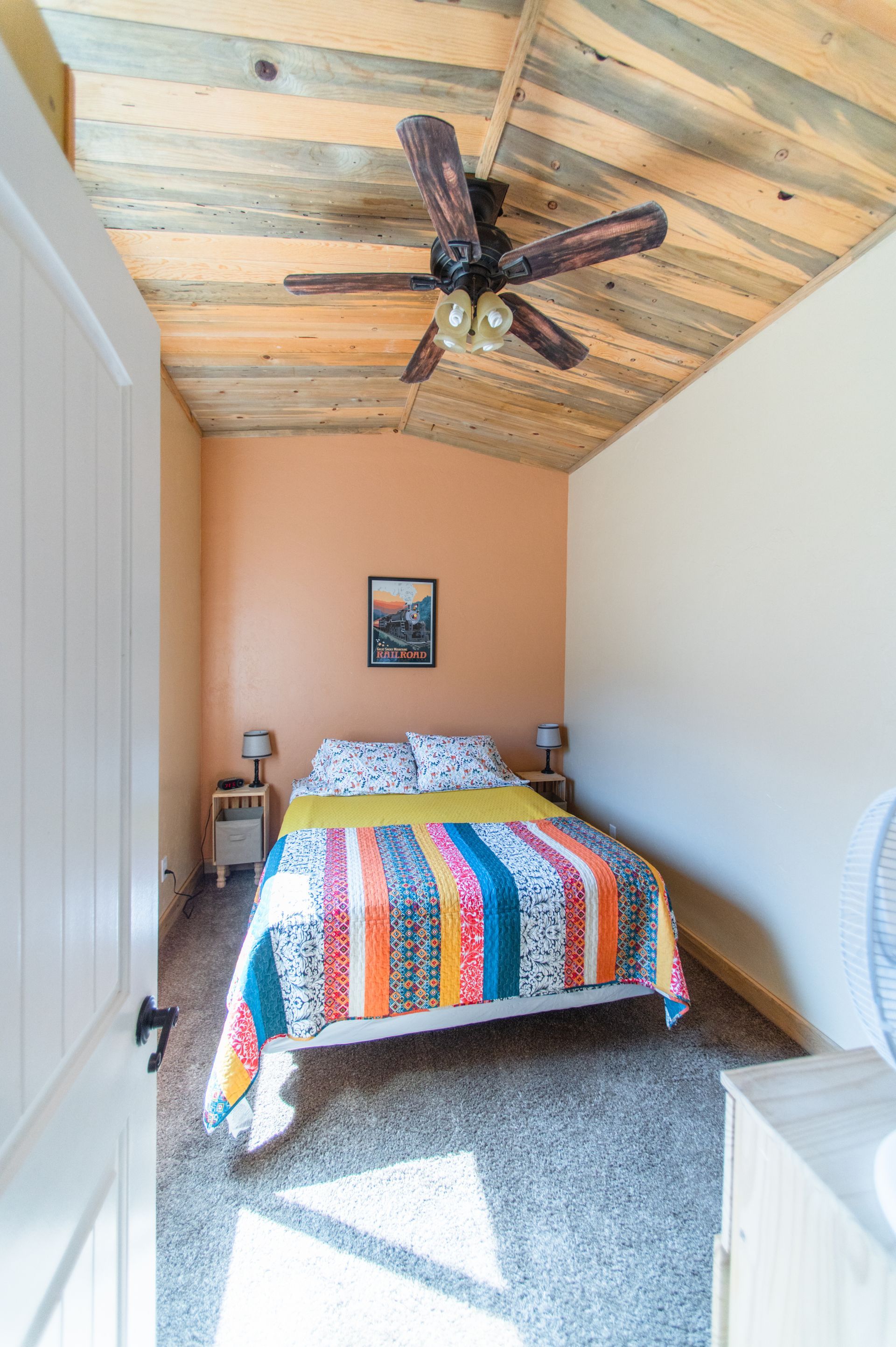 A bedroom with a bed and a ceiling fan.