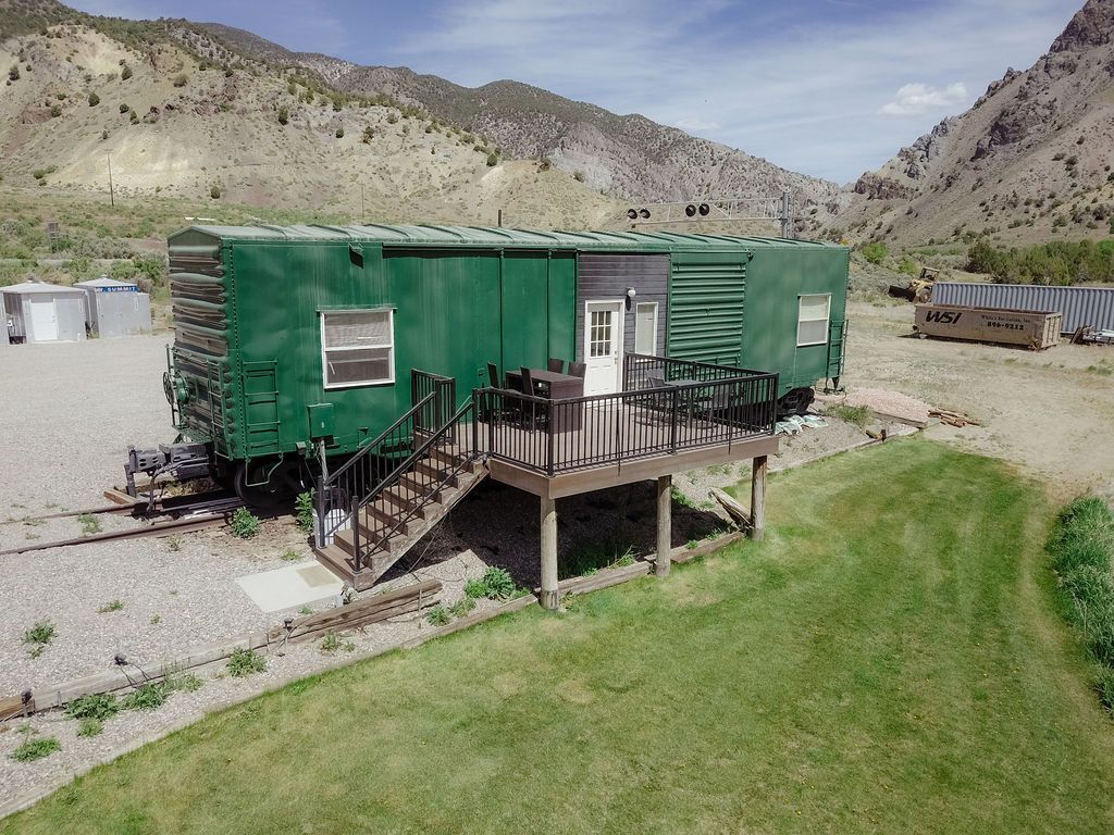 An aerial view of a green train car with a deck and stairs.