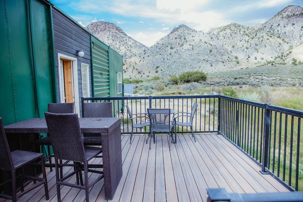 A deck with a table and chairs and mountains in the background.