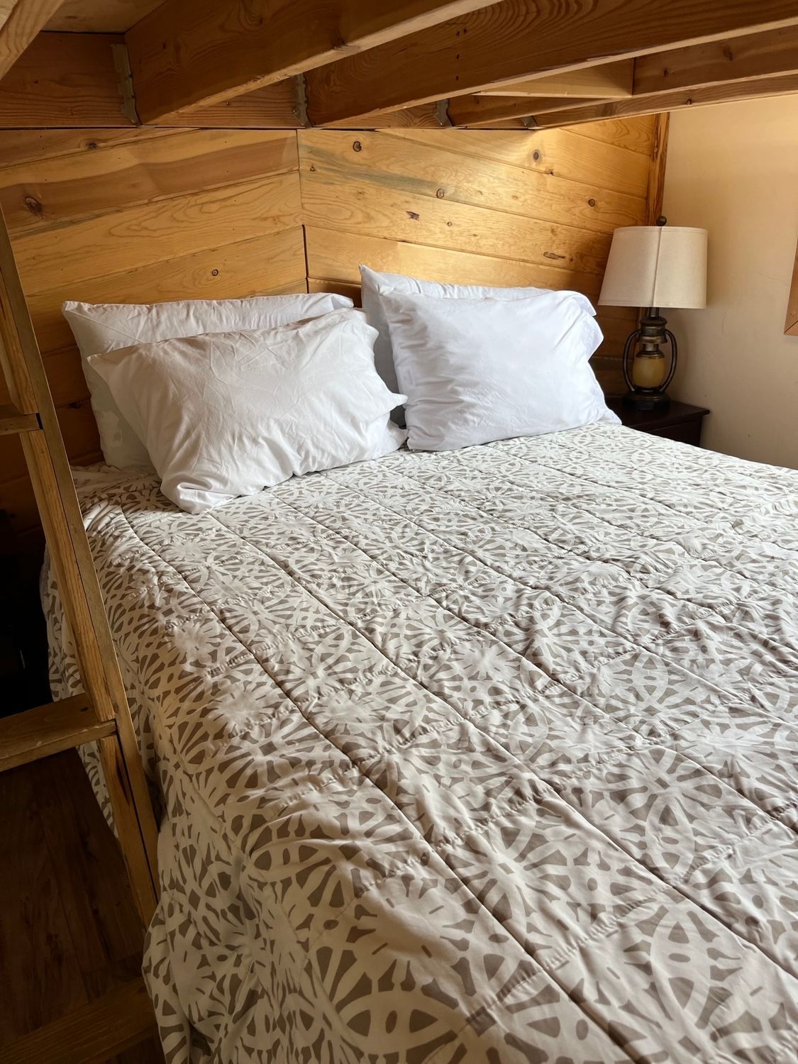 A bed with white sheets and pillows in a bedroom with a wooden headboard.