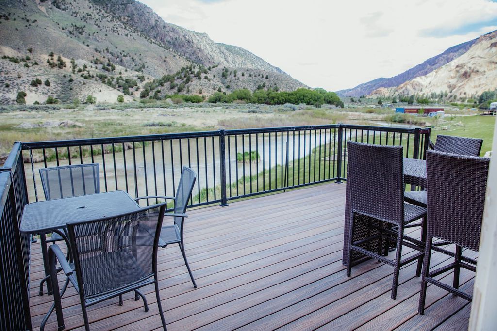 A deck with a table and chairs and mountains in the background.