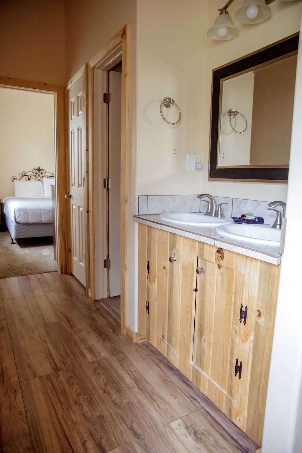 A bathroom with two sinks , a mirror and wooden cabinets.