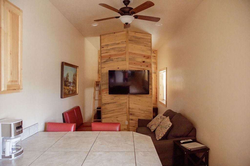 A living room with a couch , table , television and ceiling fan.